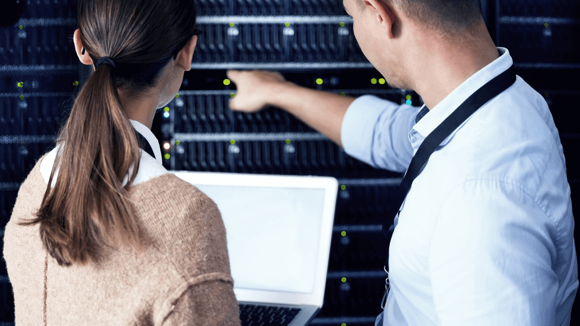 two technicians examining a server rack in an IT room